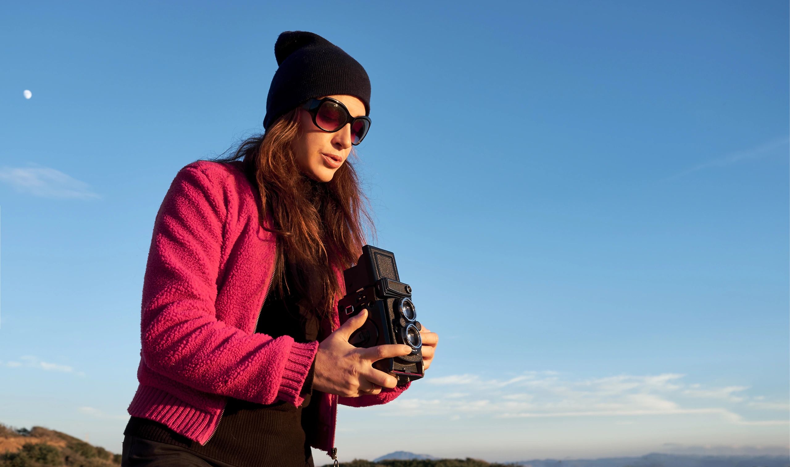 Photographer outdoors capturing creative portraits under a clear sky