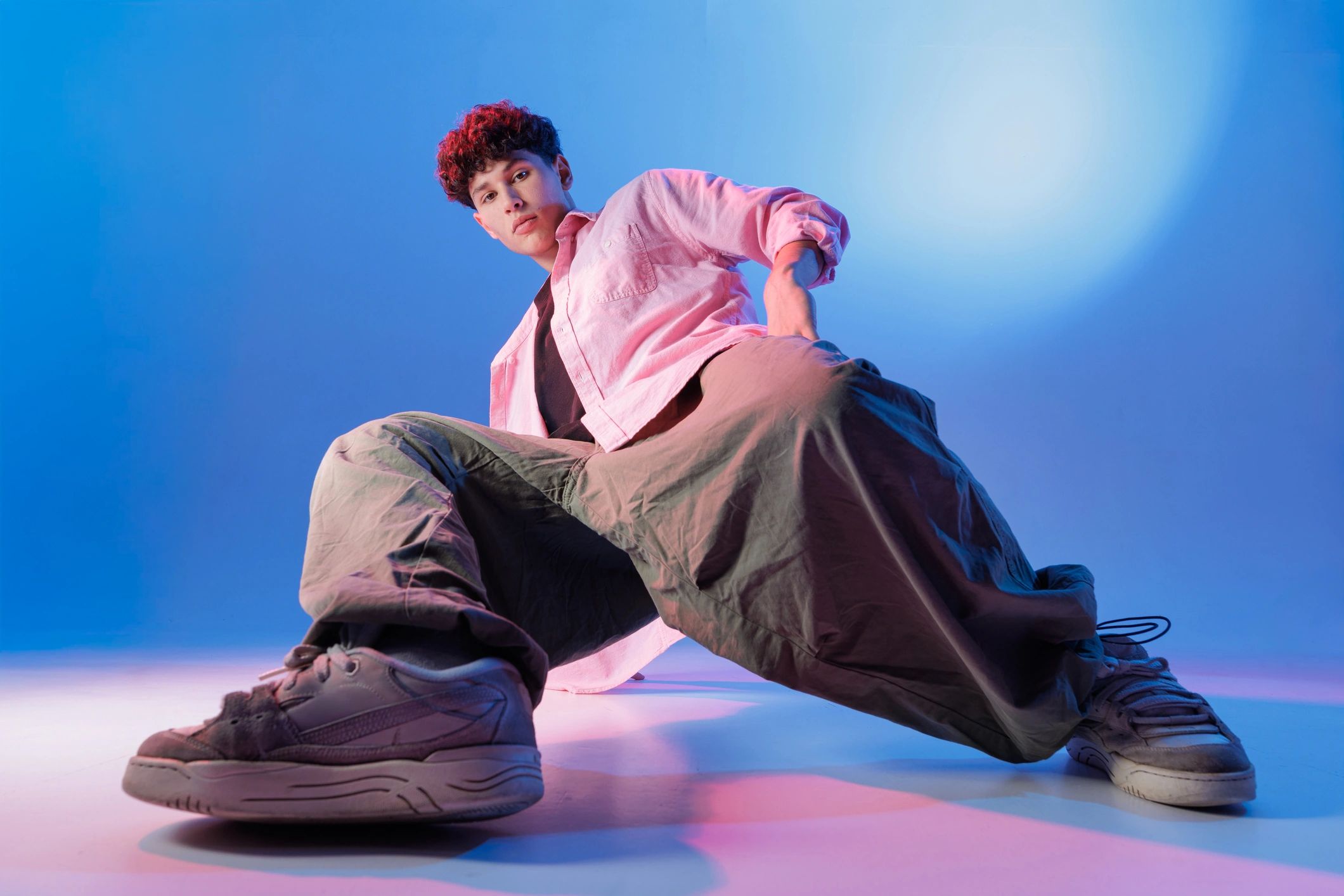 Low-angle streetwear portrait in a neon-lit studio