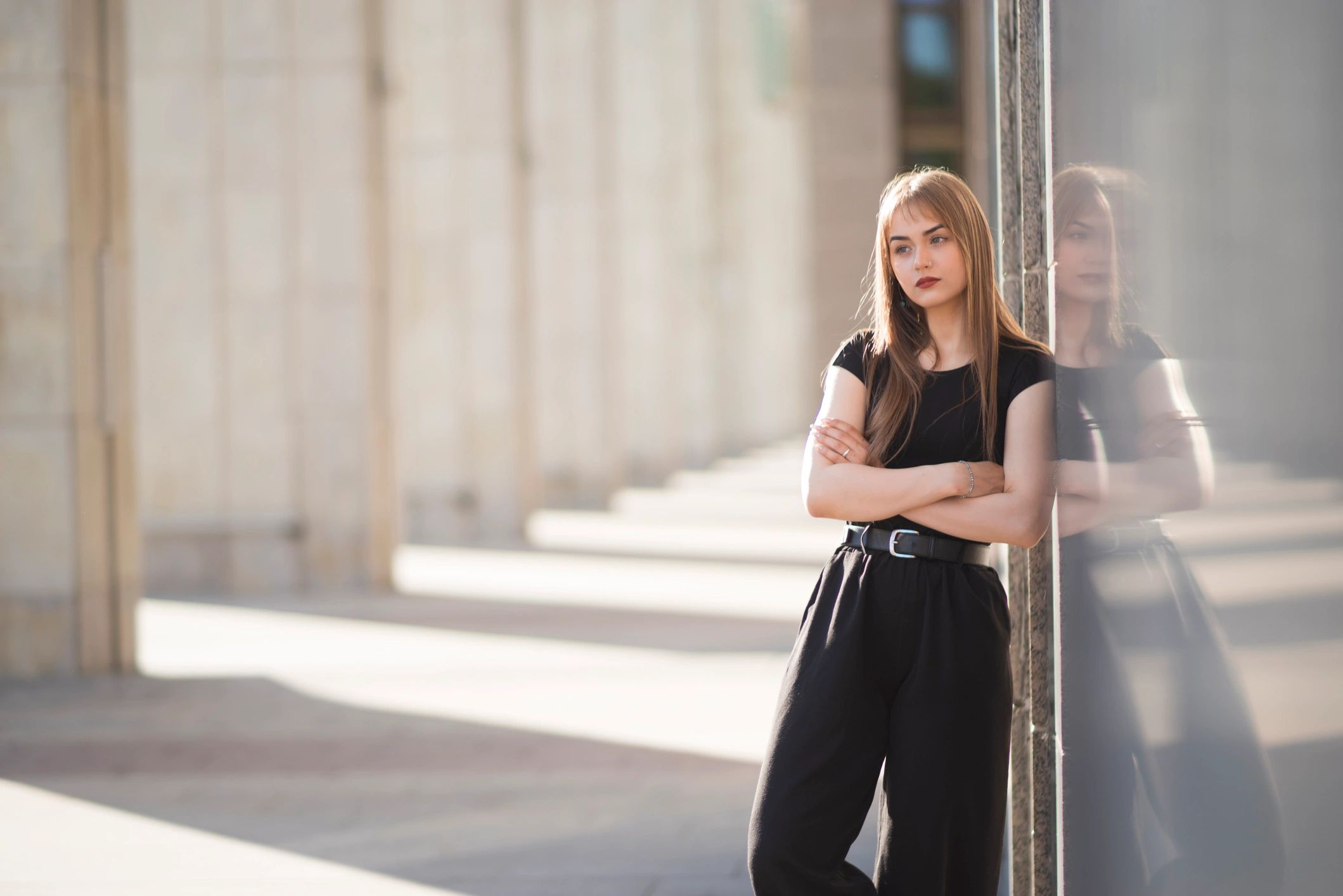 Confident young woman leaning on a granite wall in an urban editorial portrait